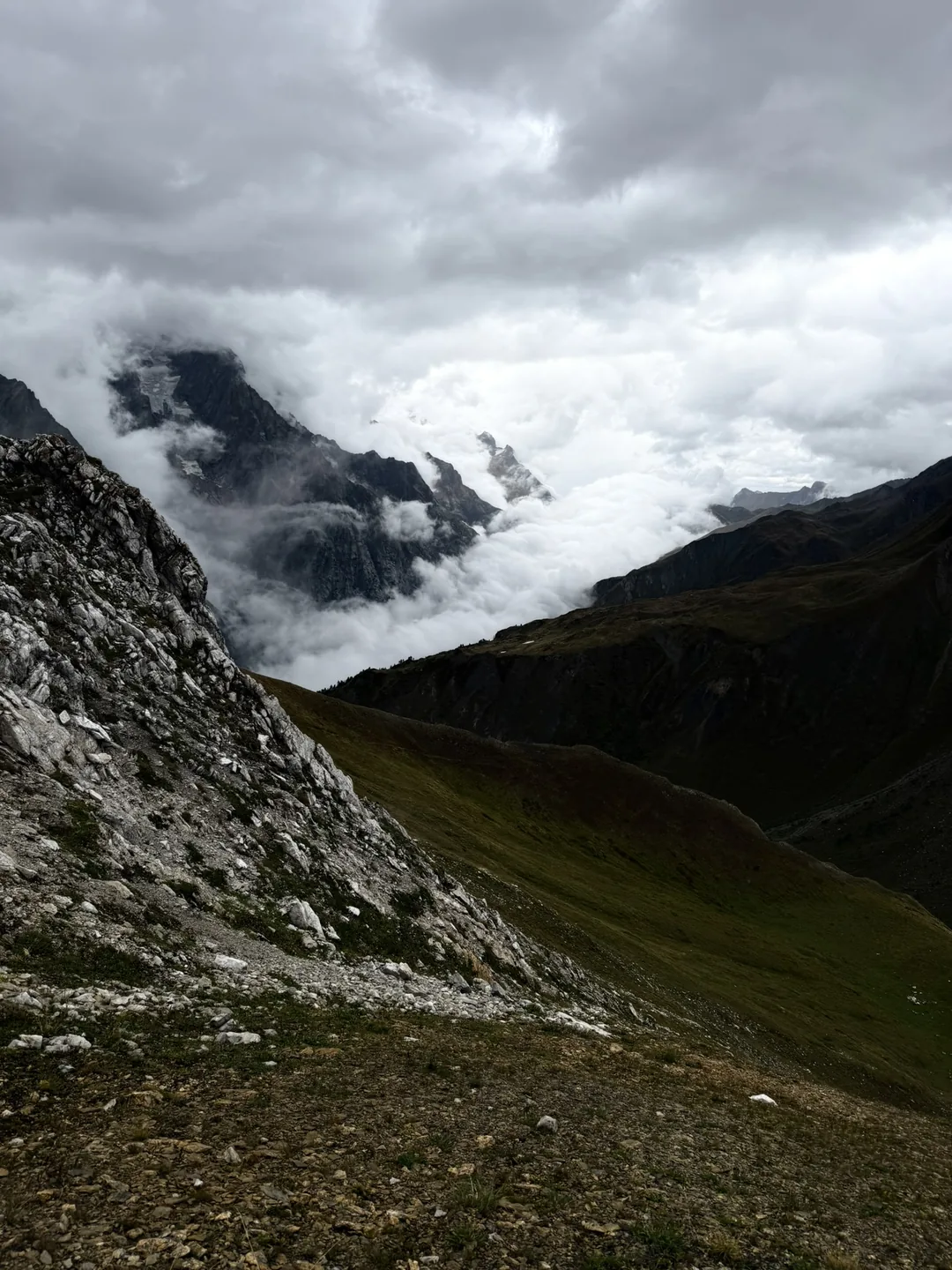 A cloud inversion filling the valley below rock faces streaked with old snow.